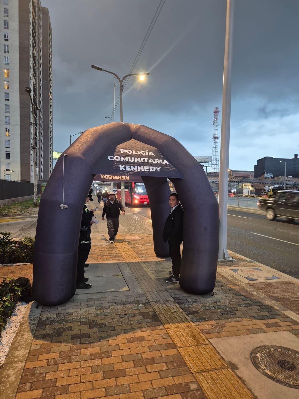 Arco inflable de la Policía Comunitaria de Kennedy instalado sobre el andén de la Avenida Carrera 68, frente a Iconik 68, al anochecer