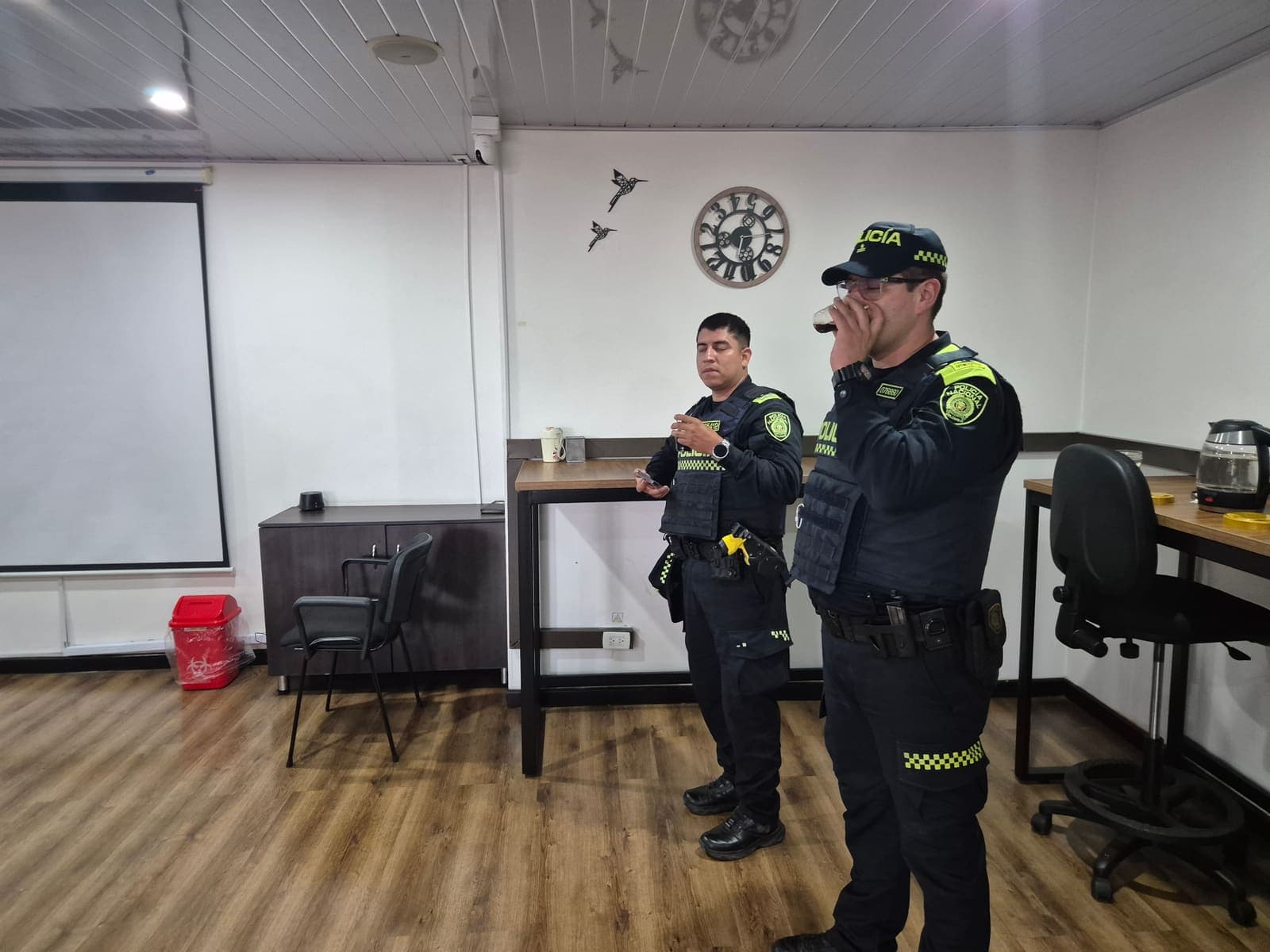 Dos patrulleros de la Policía Nacional junto a la pantalla de proyección del salón social, durante la capacitación del programa AIDE